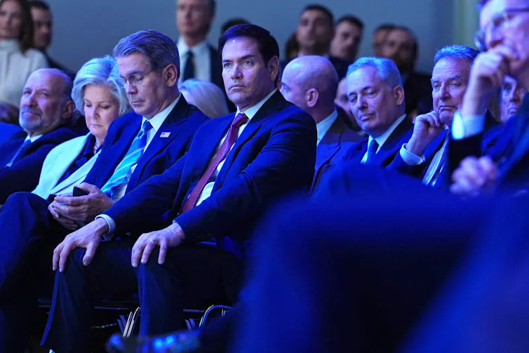 Several men sit in a conference hall.