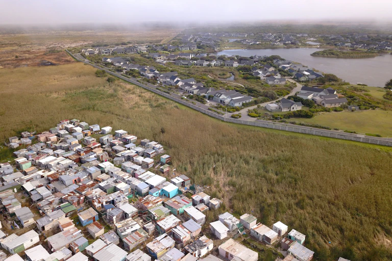 Aerial view of wealthy suburb with informal housing next to it.