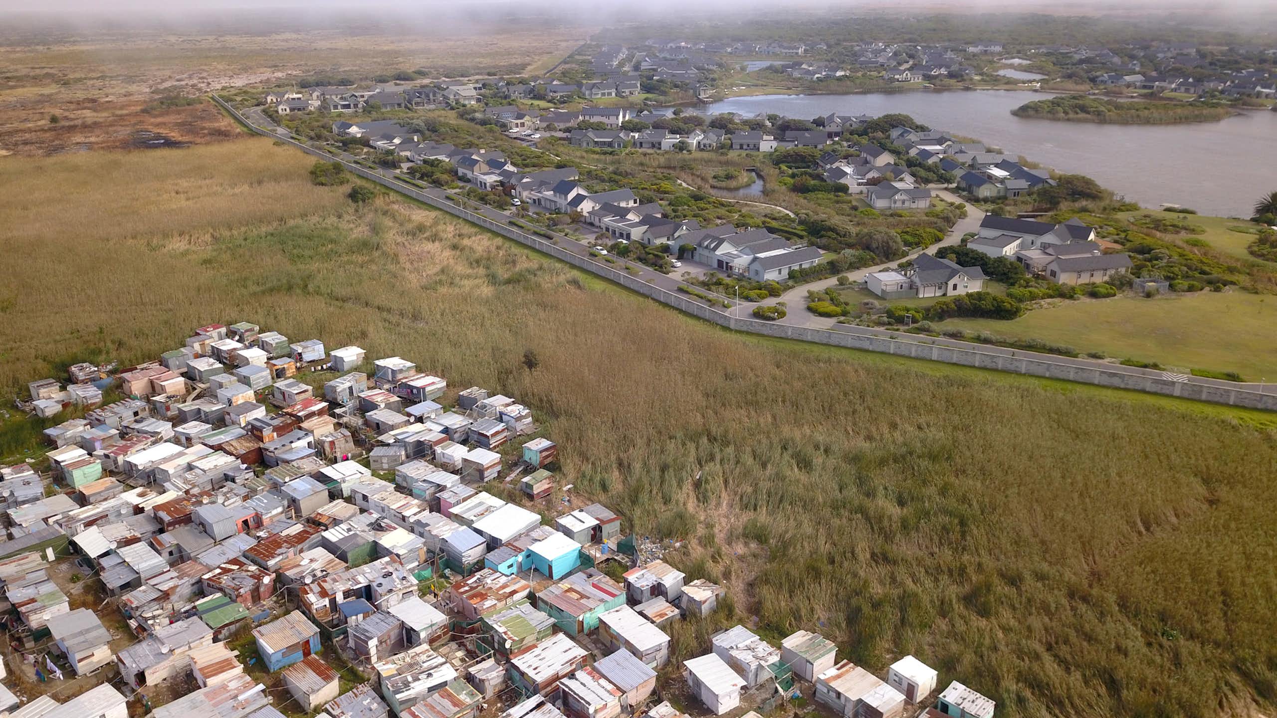 Aerial view of wealthy suburb with informal housing next to it.