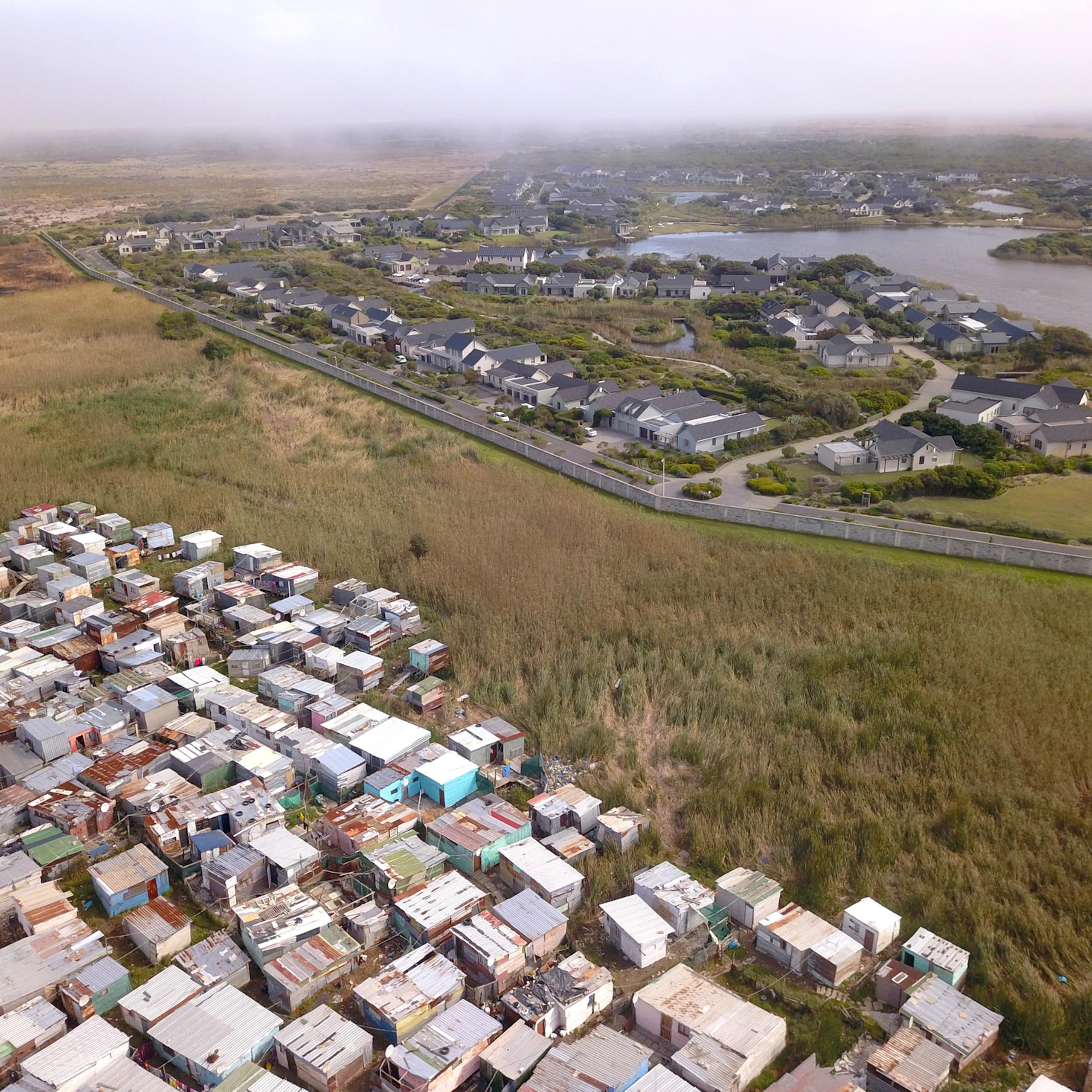 Aerial view of wealthy suburb with informal housing next to it.