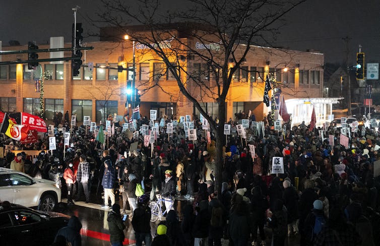 A crowd of protesters on a city corner in the night.