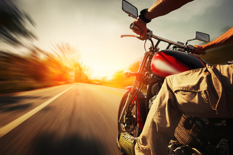 A biker riding a motorcycle on an empty road at dusk