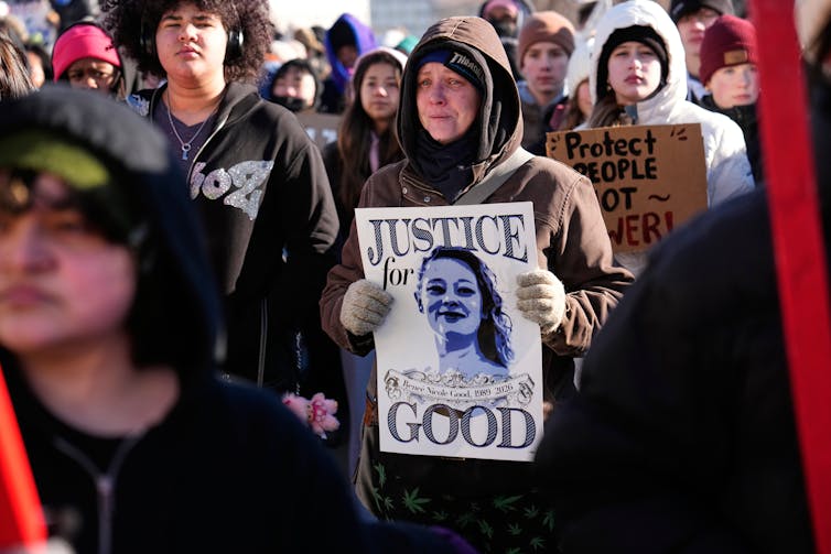 women protesters in winter coats and jackets hold signs