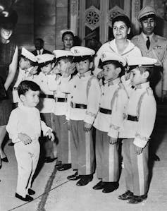 El ascenso de Reza Pahlavi: ¿líder de la oposición iraní u oportunista? 1 Un joven se encuentra frente a una columna de niños con uniformes militares.