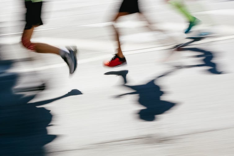 Blurred shot of the legs and shoes of three people running