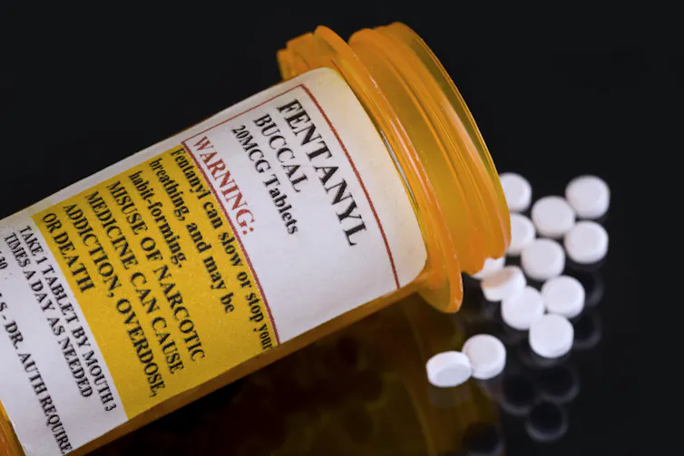 Close-up of a prescription bottle of fentanyl with white pills spilling out on the table.