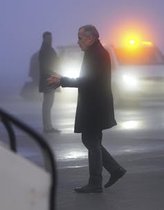 Un hombre delgado es visto de perfil al anochecer entrando a un avión