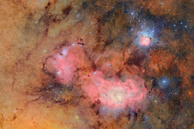 Bright clouds of pink and orange dust, surrounded by stars.