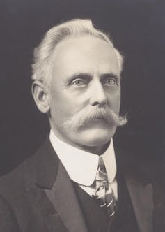 A black and white photo of a man with a white moustache