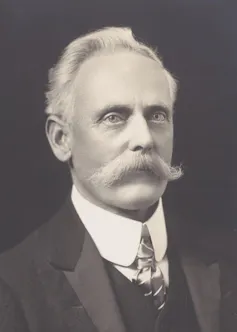 A black and white photo of a man with a white moustache