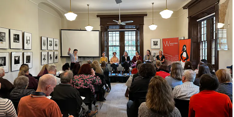 People sitting in a room watching a talk on stage