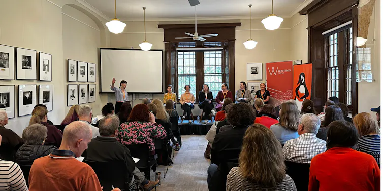 People sitting in a room watching a talk on stage