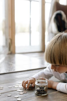 A child putting coins in a glass jar