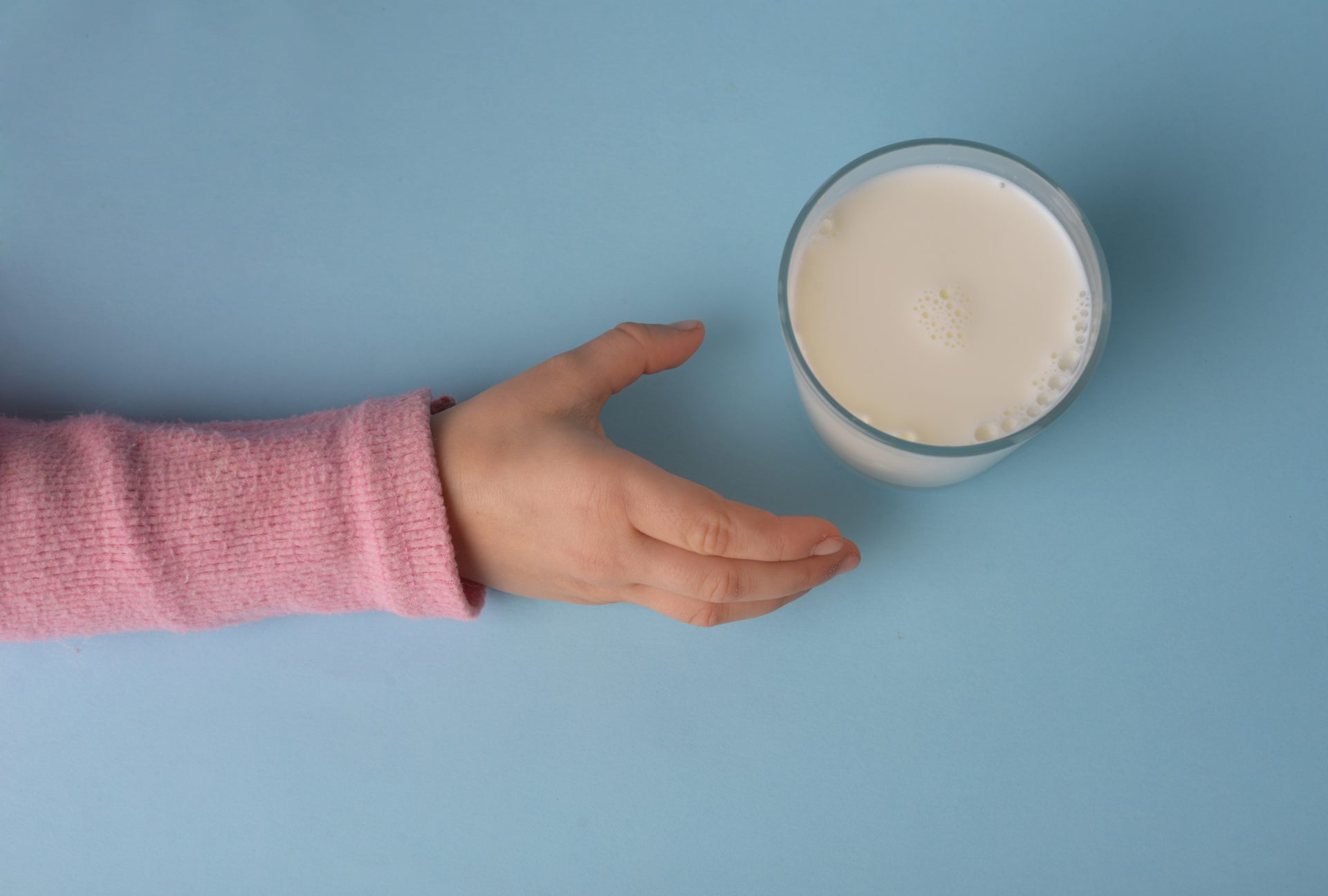 Una mano infantil junto a un vaso de leche