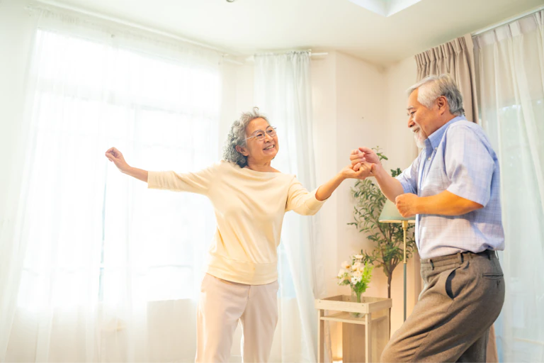 Happy senior couple dancing together in living room