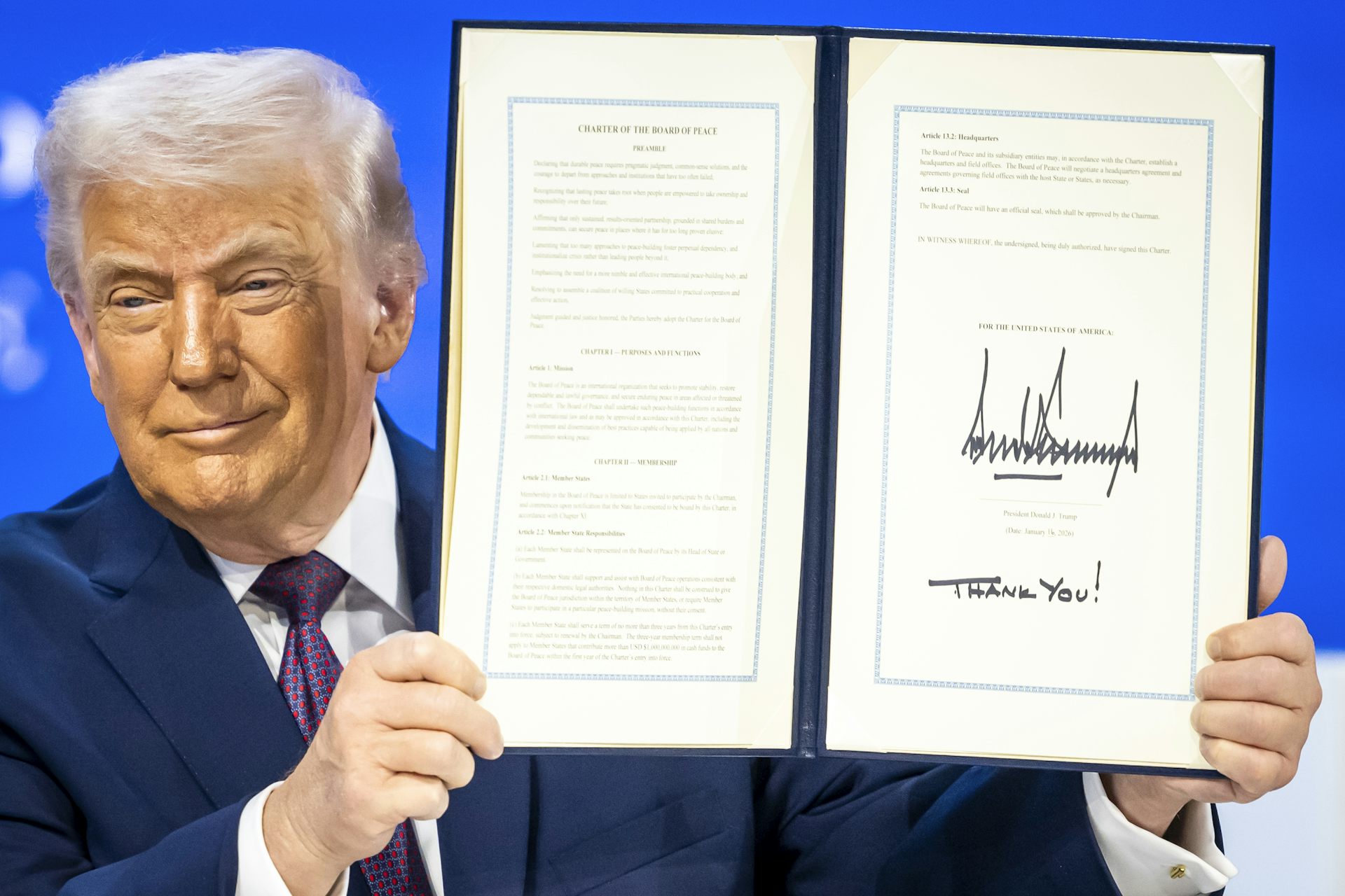 Donald Trump holding up a document with his signature on it. 