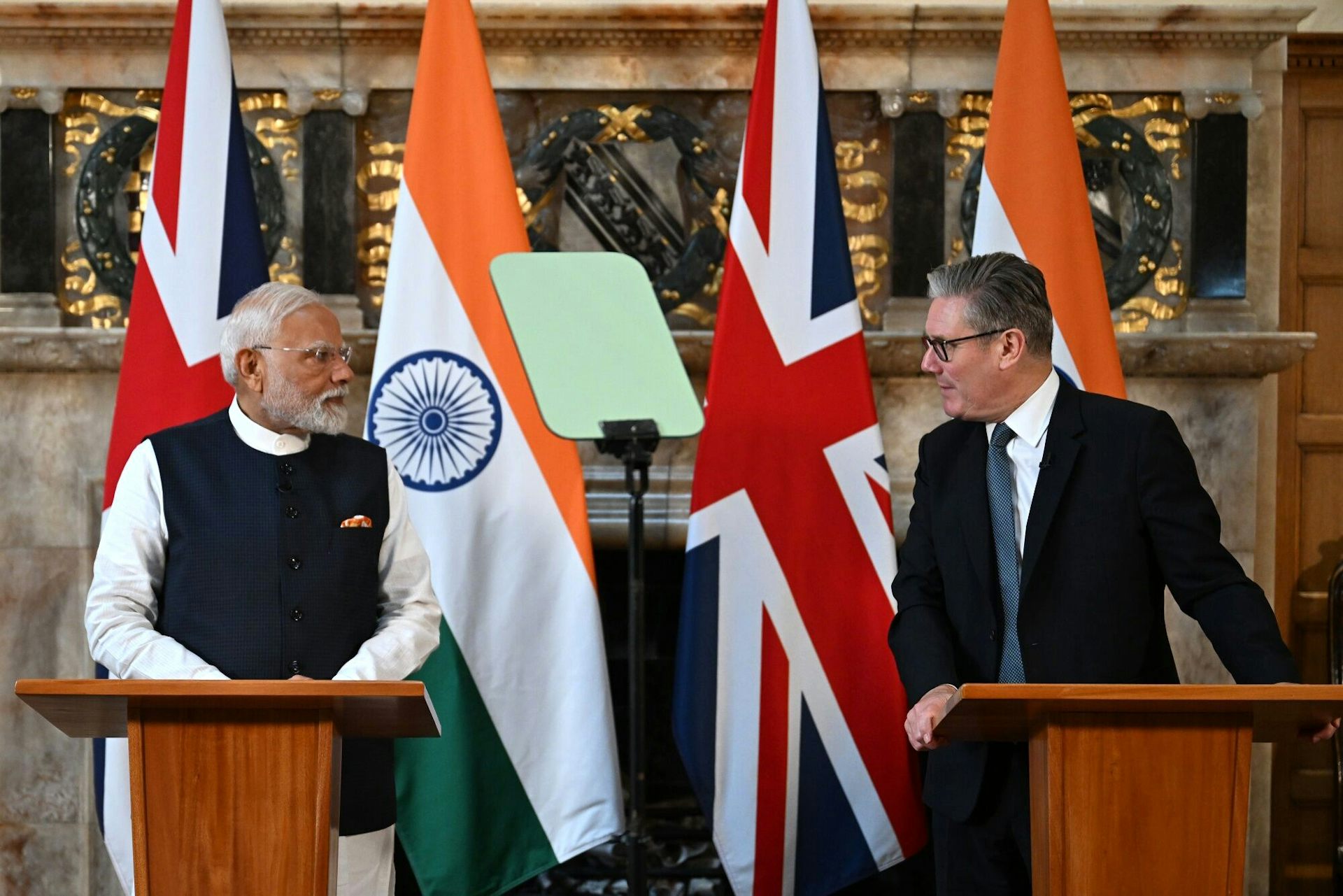 Prime ministers Modi and Starmer at podiums.