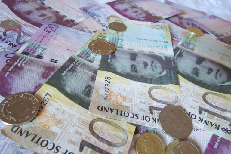 selection of bank of scotland bank notes and sterling coins.