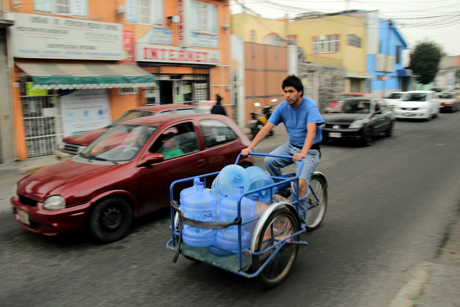 A man on a bicycle carrying water bottles.