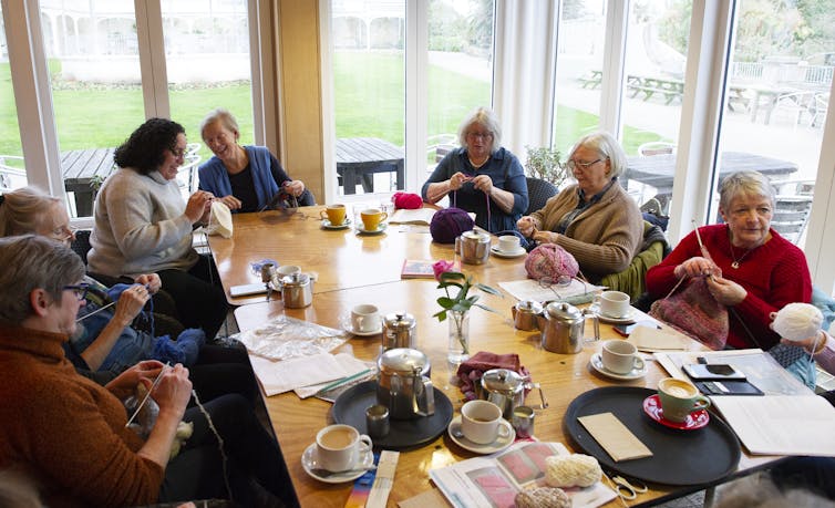 Older women knitting together and socializing in a community space.