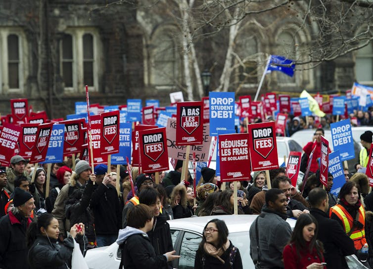 El proyecto de ley 33 de Ontario plantea serias preocupaciones sobre la equidad en los campus y los derechos de los estudiantes 1 La gente porta carteles de protesta con lemas como alivio de la deuda estudiantil.