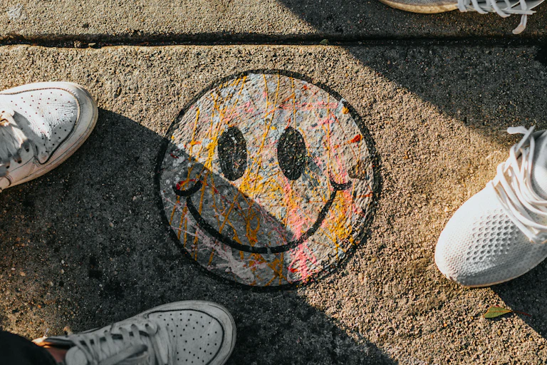 People stand around a colourful smiley face painted on a footpath.