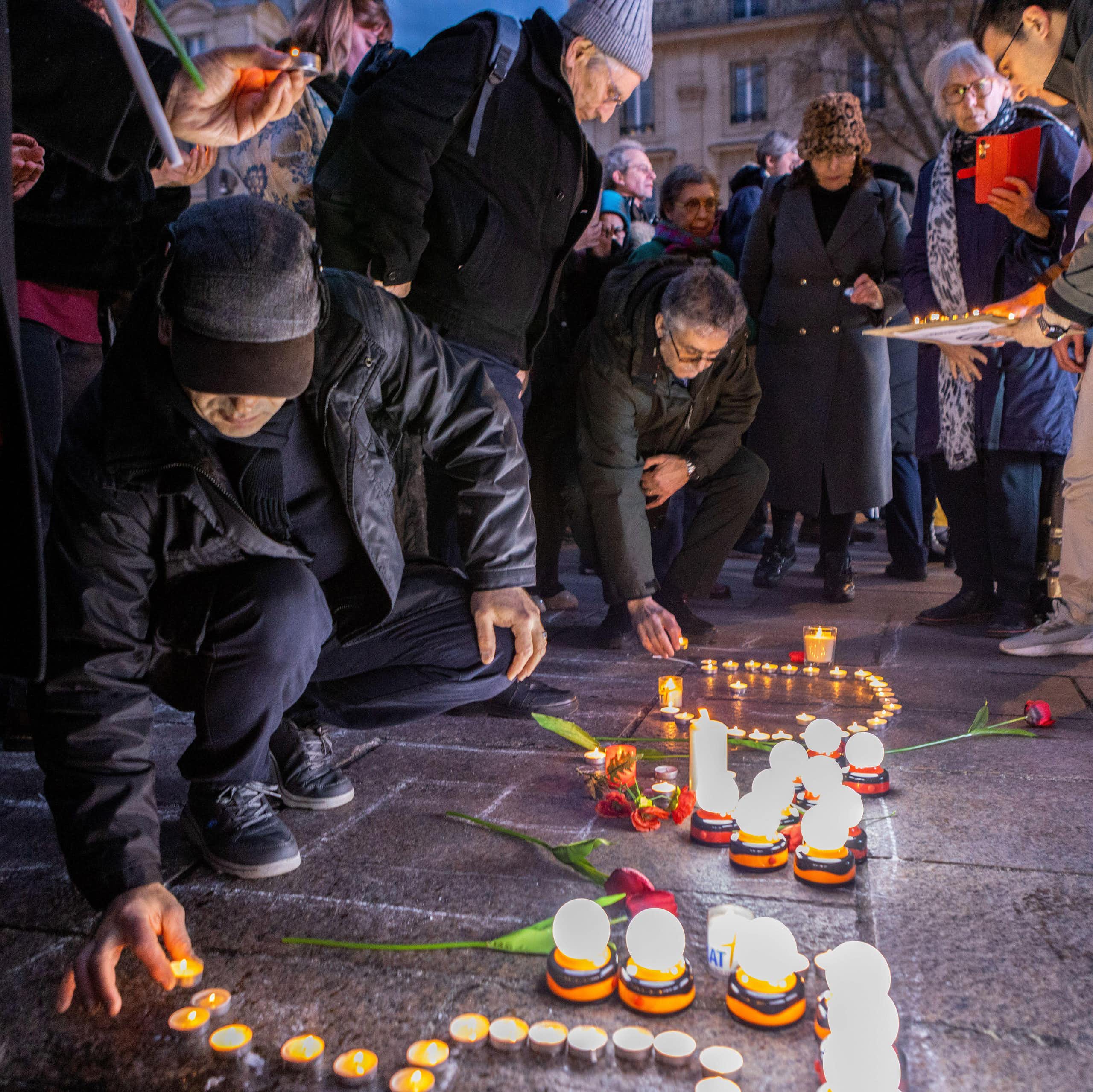 Candles being lit by a kneeling person at a vigil in support of Iranian protest.