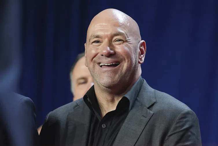 A man wearing a sport jacket smiles.
