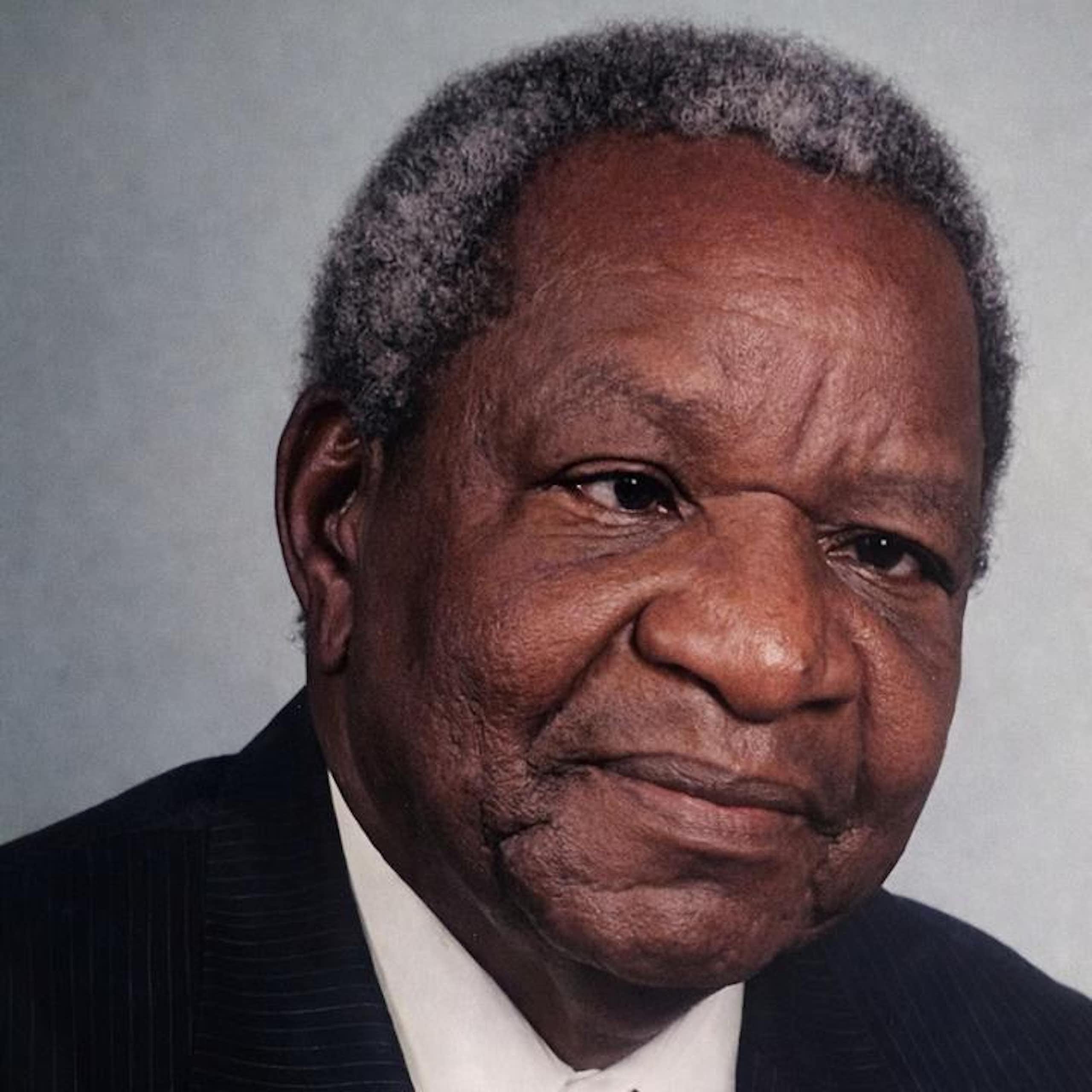 Head and shoulders of an African man in a suit and red tie