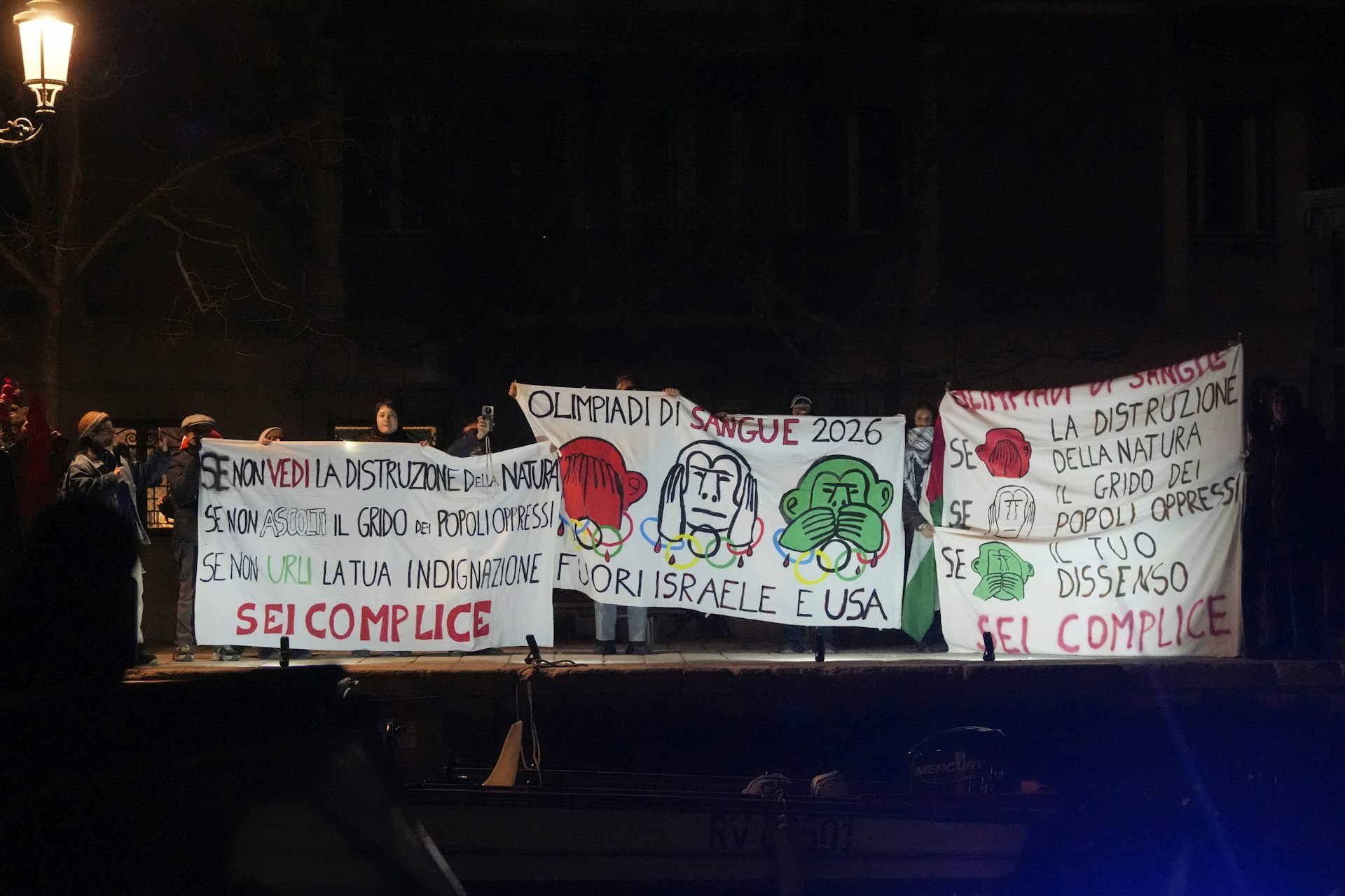People holding protest signs along the banks of a canal