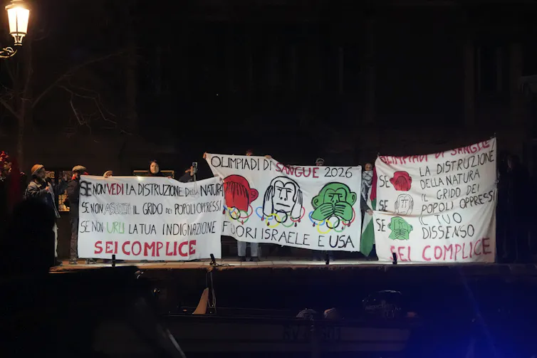People holding protest signs along the banks of a canal