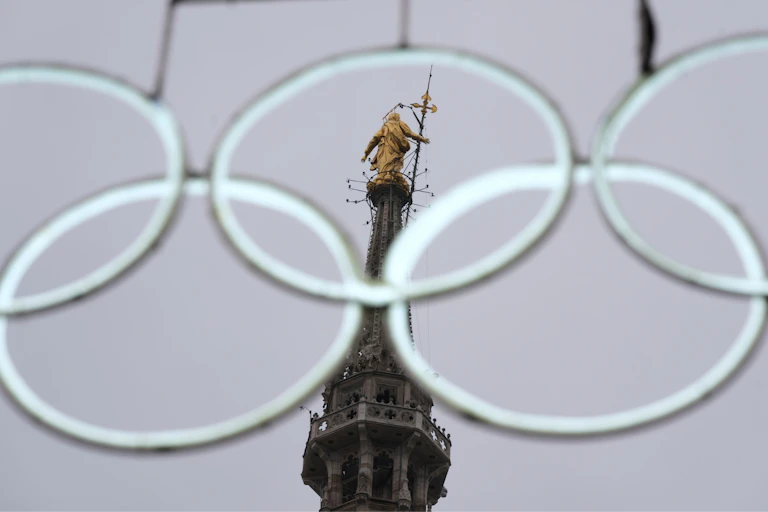The statue of the Virgin Mary seen through the middle of a set of white, intertwined white rings