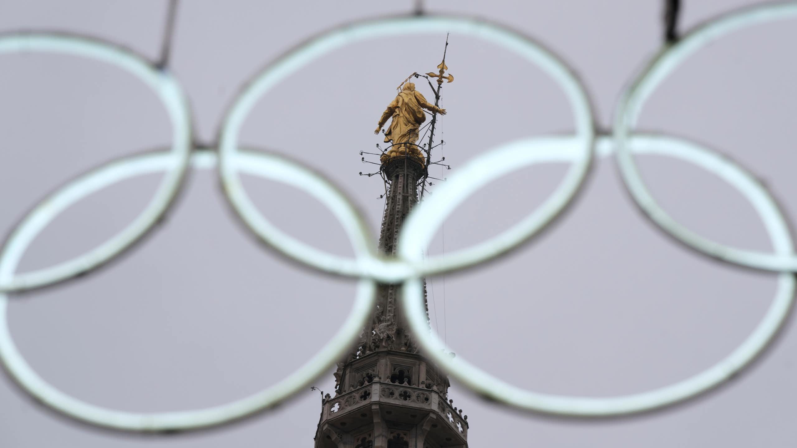 The statue of the Virgin Mary seen through the middle of a set of white, intertwined white rings