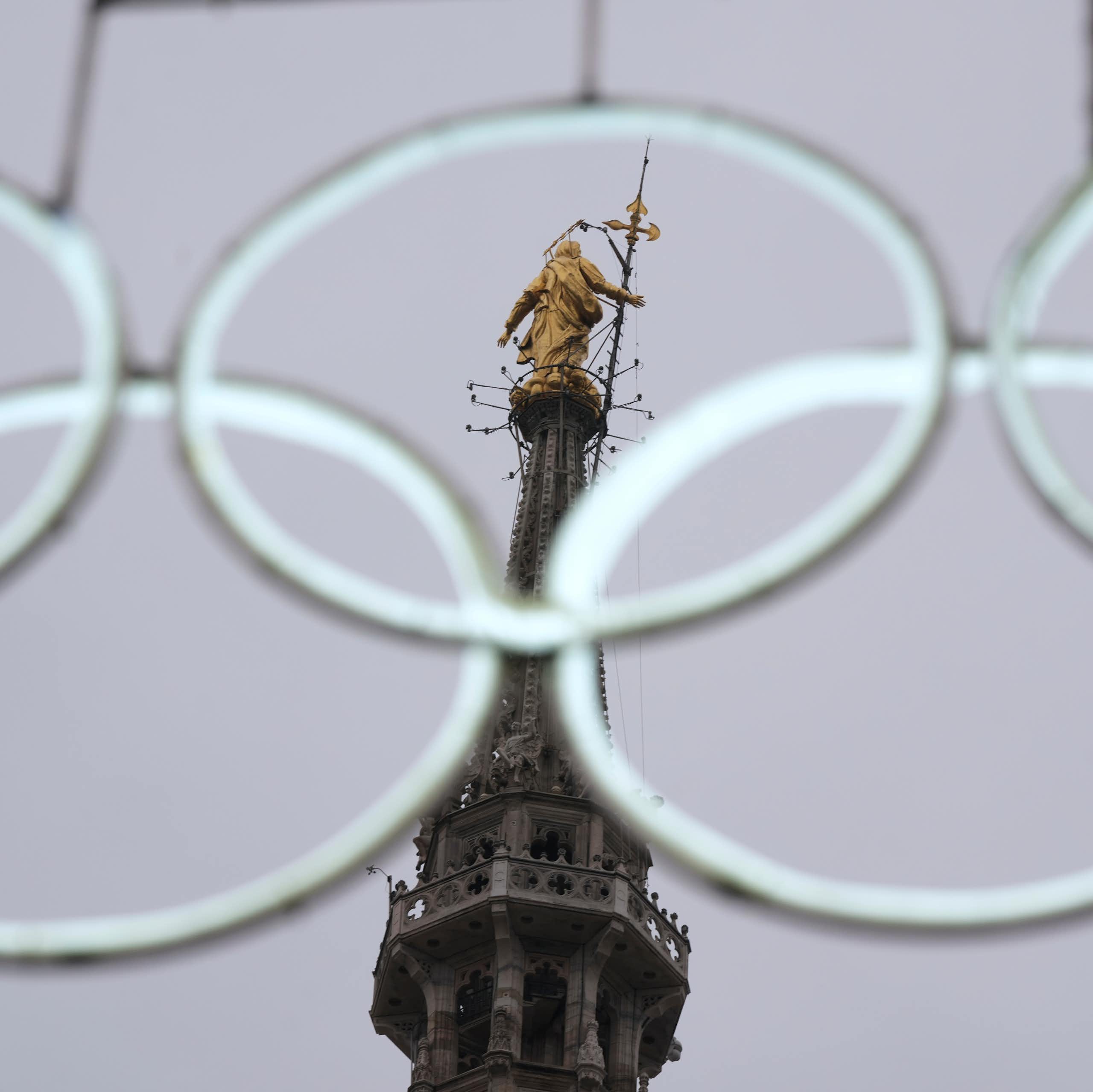 The statue of the Virgin Mary seen through the middle of a set of white, intertwined white rings