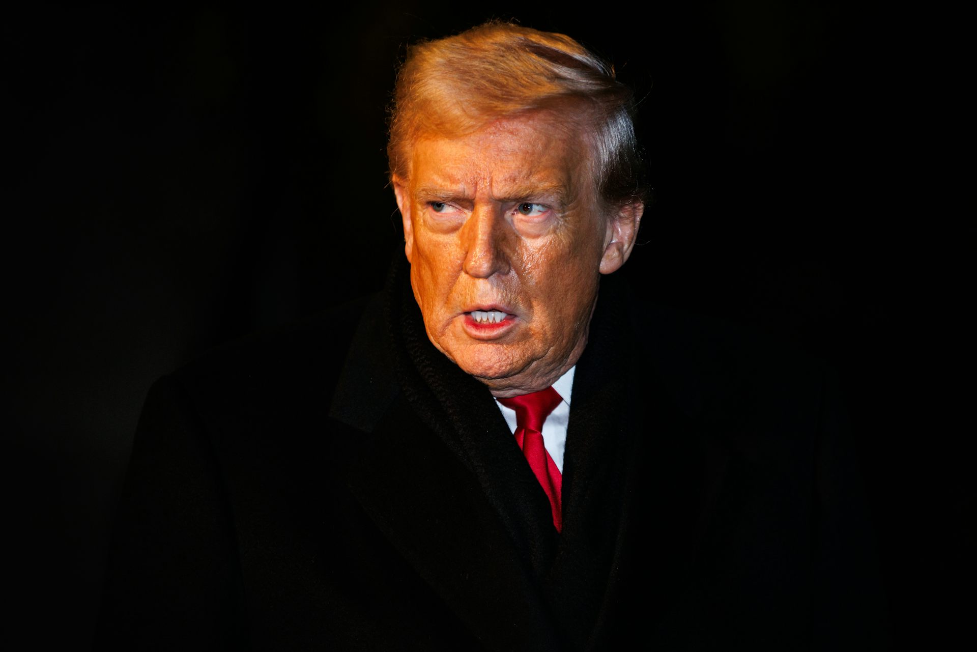 A man in a suit and red tie stands.