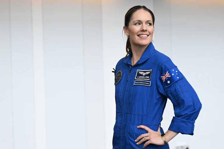 A smiling woman dressed in an astronaut jumpsuit, smiling