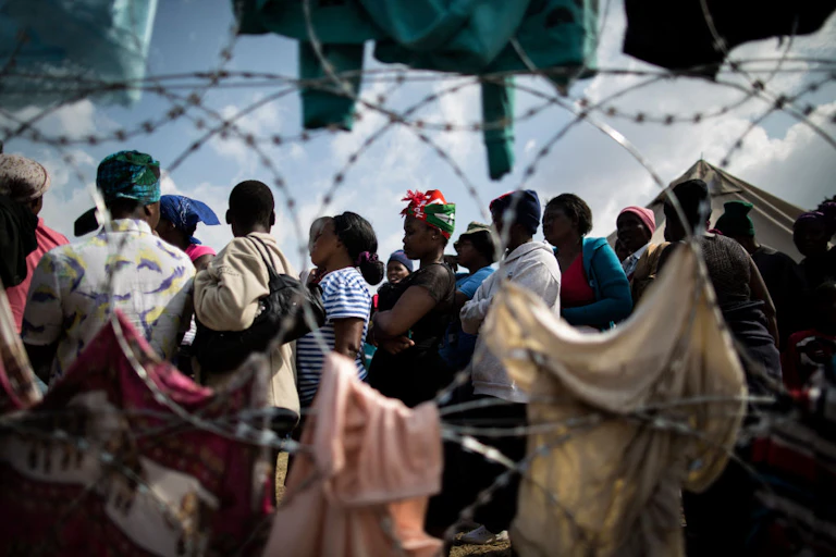 Group of people seen beyond razor wire fencing