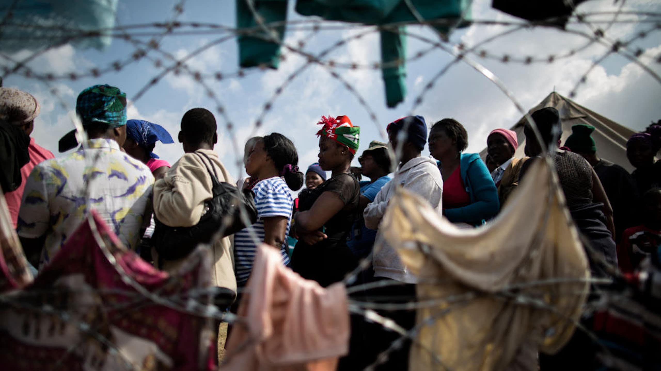 Group of people seen beyond razor wire fencing