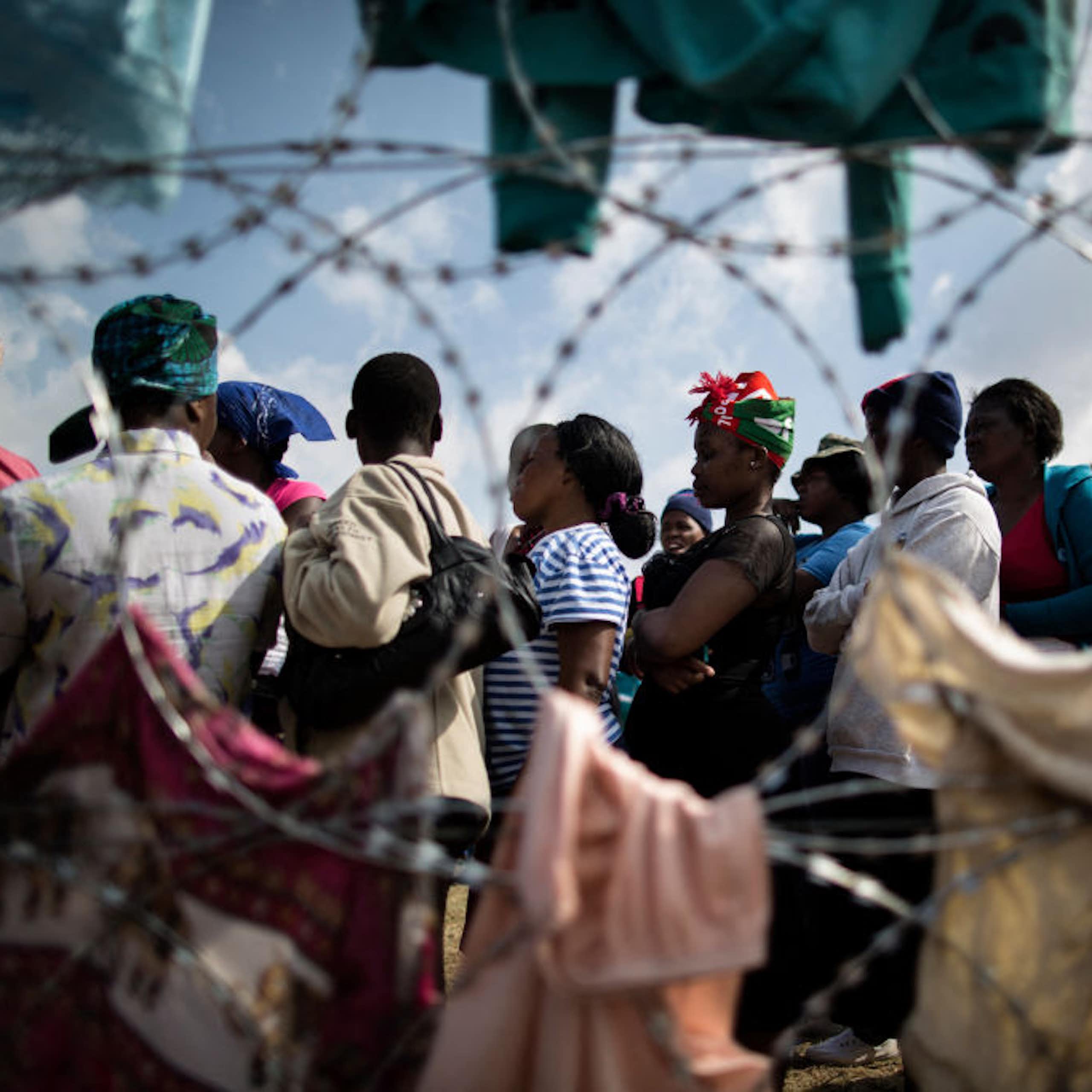 Group of people seen beyond razor wire fencing