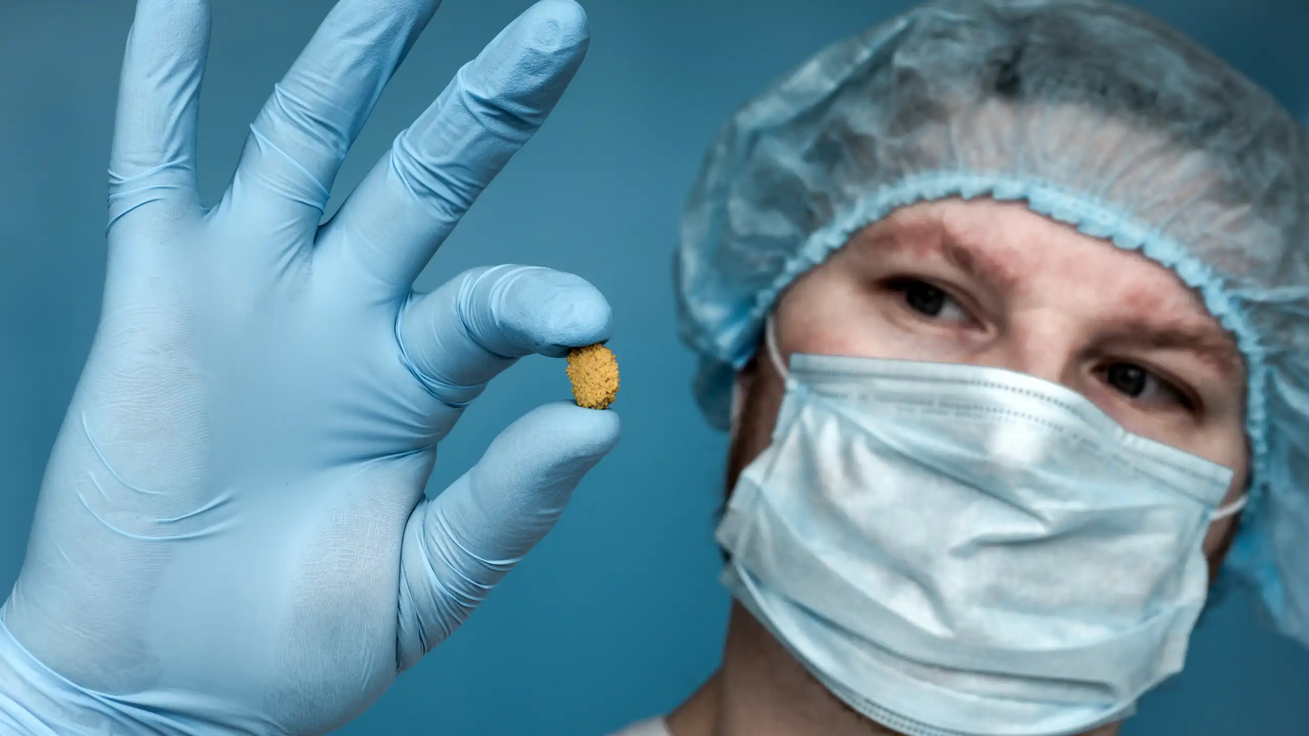 Doctor holds up a kidney stone between their fingers.