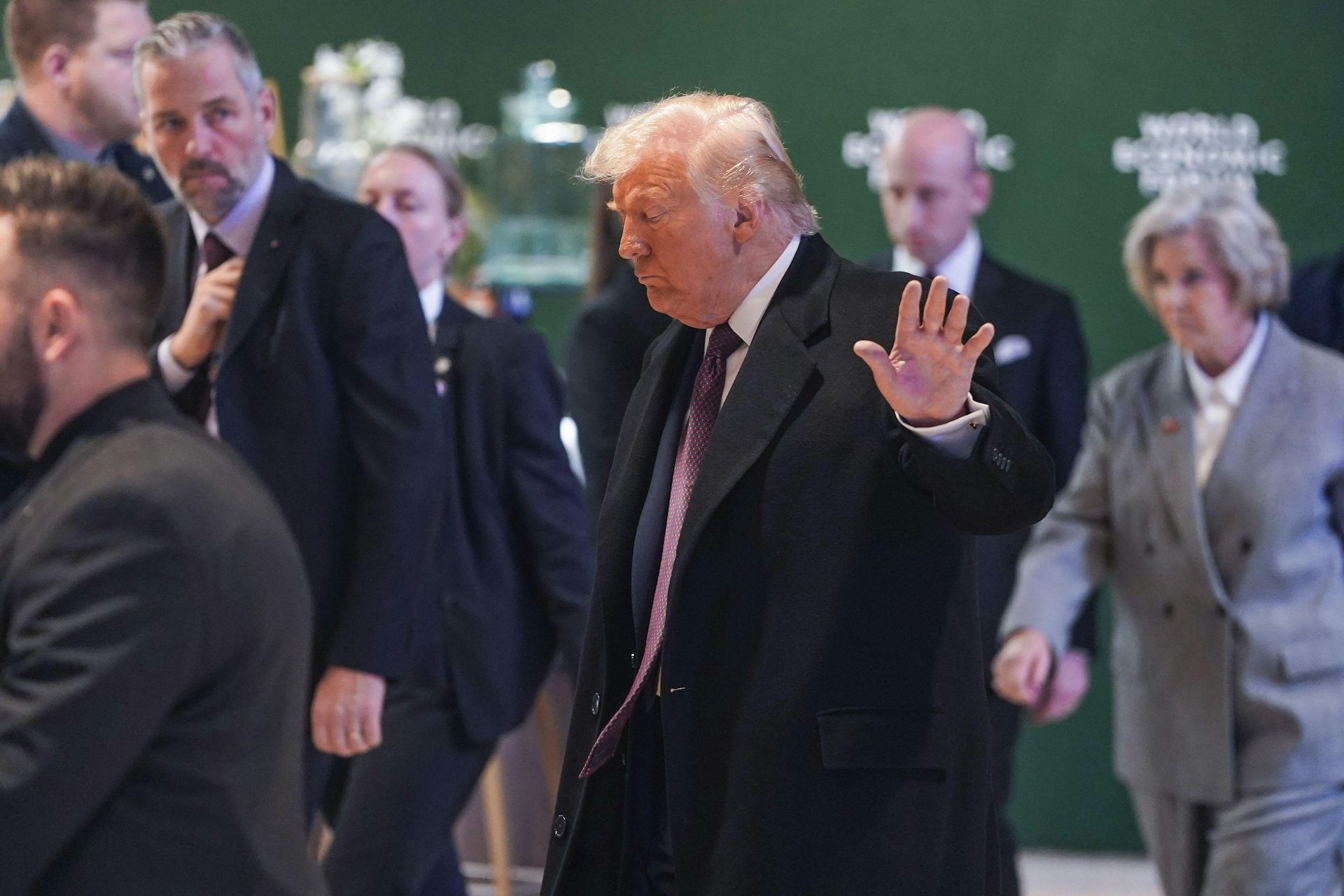 US president, Donald Trump, raises his hand towards a camera.