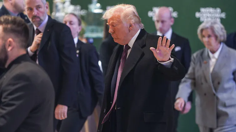 US president, Donald Trump, raises his hand towards a camera.