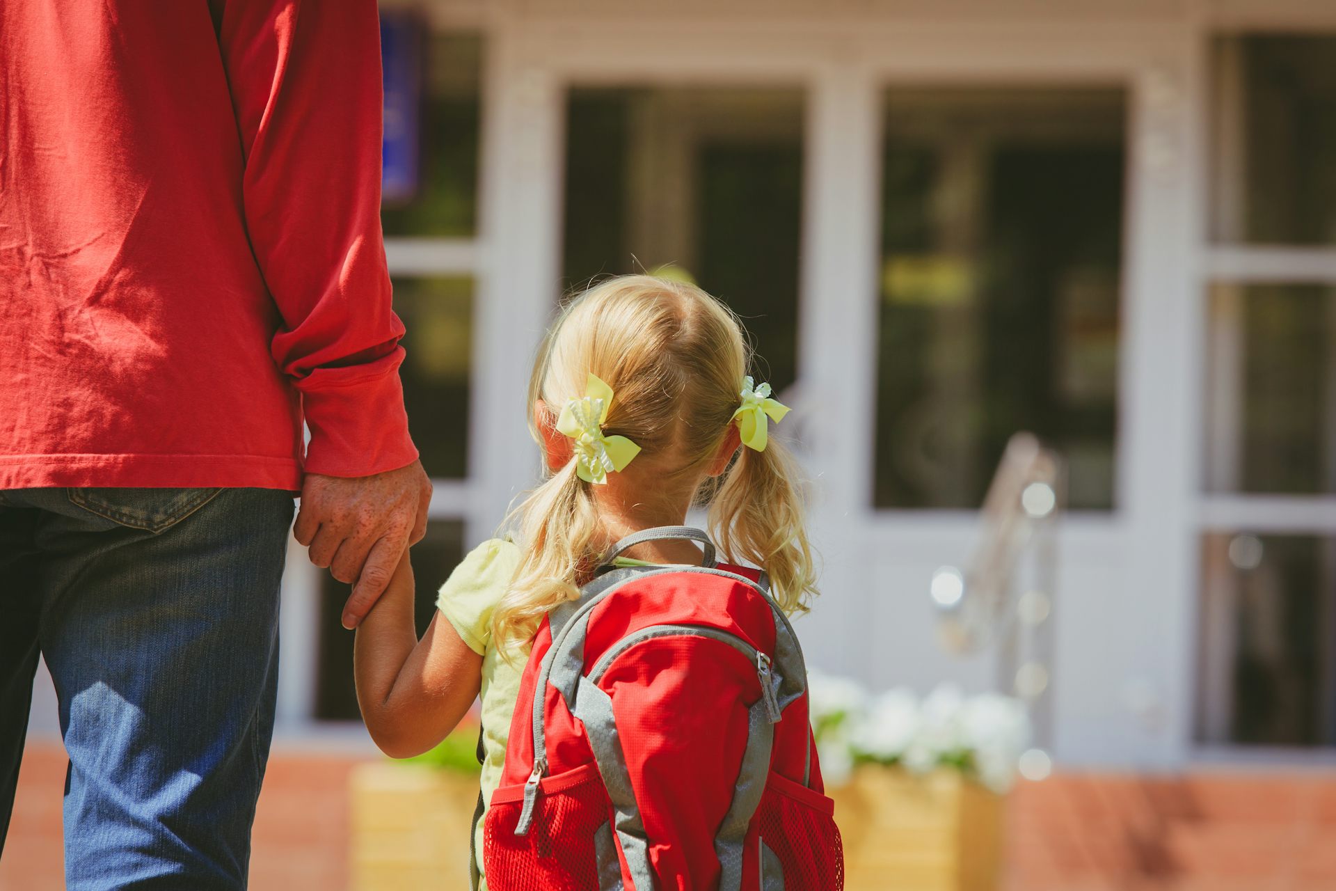 Un padre acompaña a su hija pequeña a la escuela.