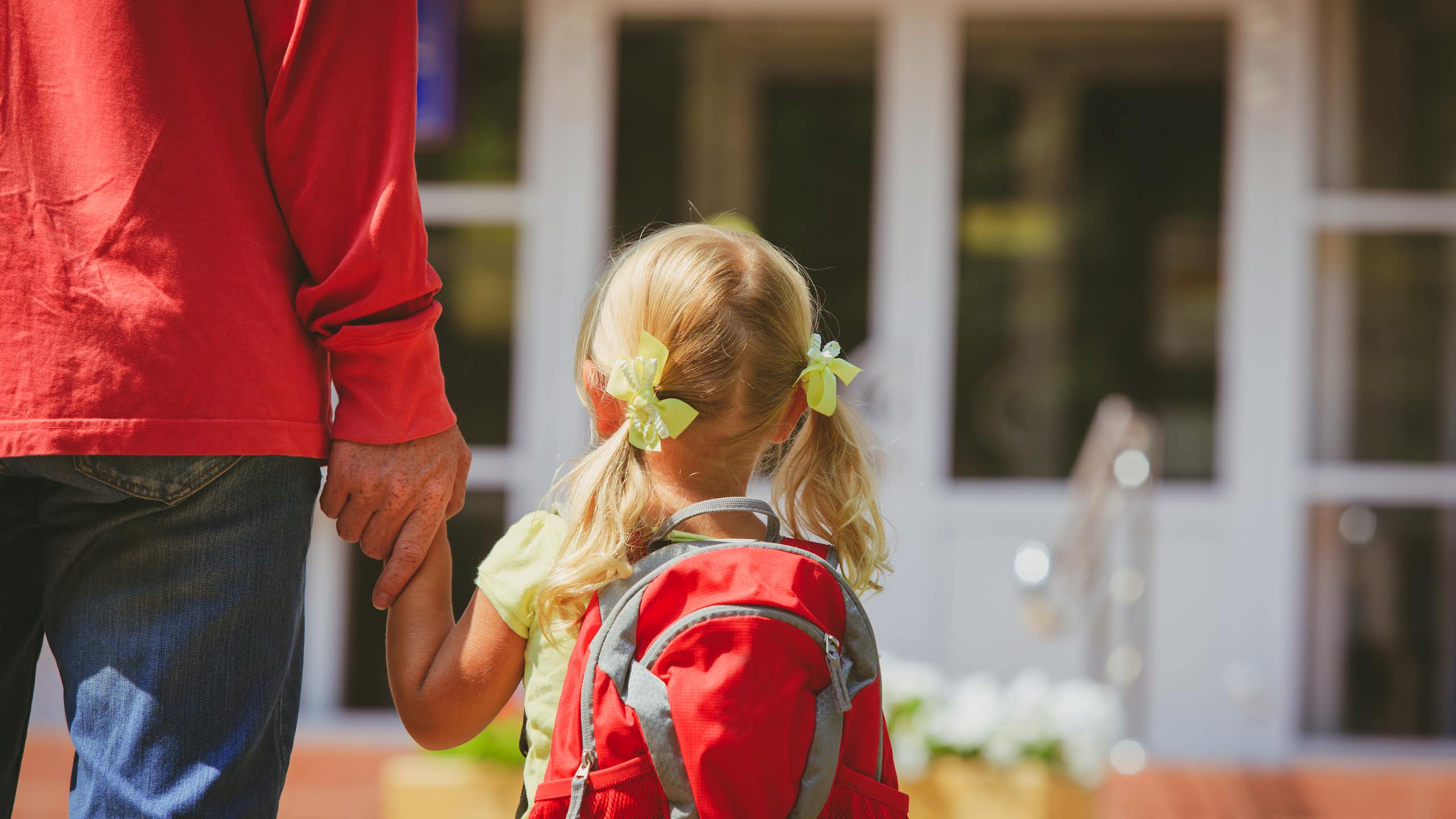 Un padre acompaña a su hija pequeña a la escuela.