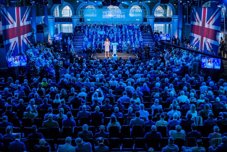 Suella Braverman on stage in front of a crowd of veterans.