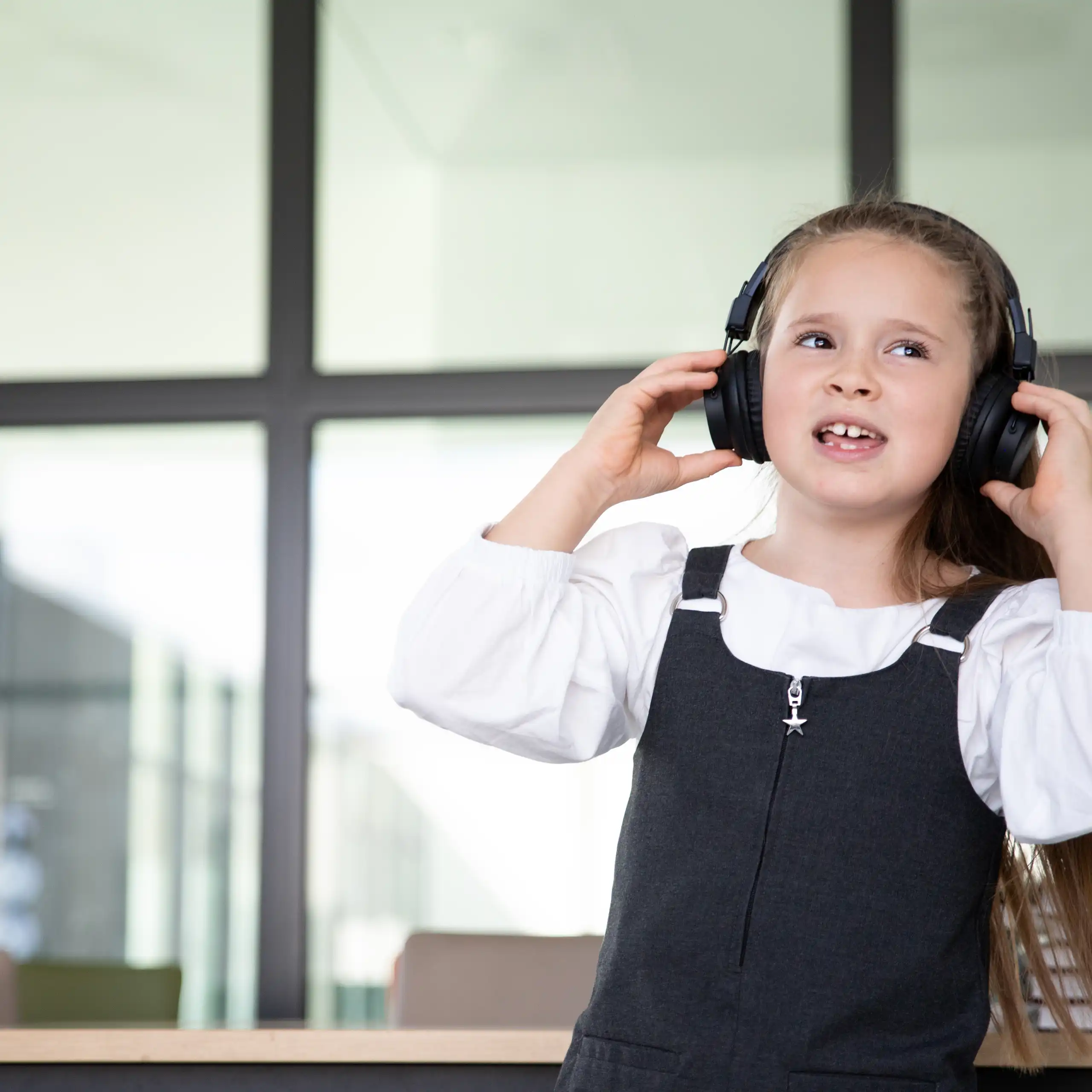 Little girl in school wearing headphones