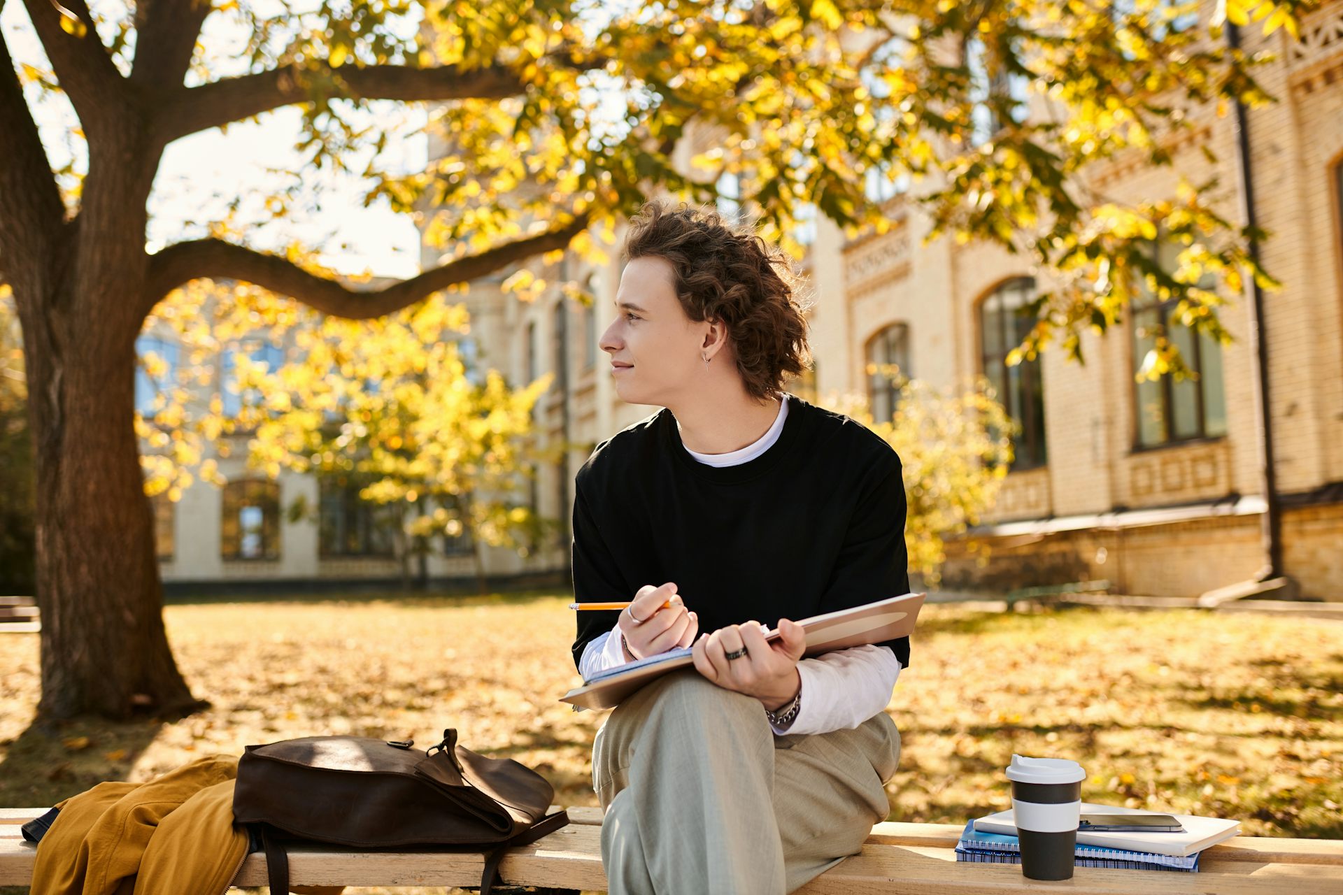 Joven sentado en un banco en un parque y dibujando