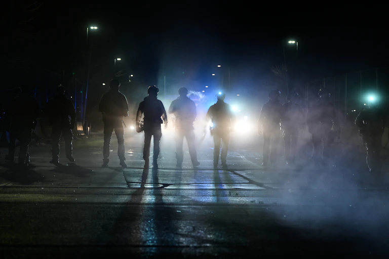 Men dressed in military gear at night.