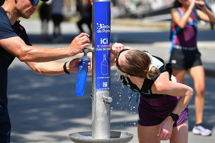 parisians drinking from a water fountain with branding of the city's public water company eau de paris.