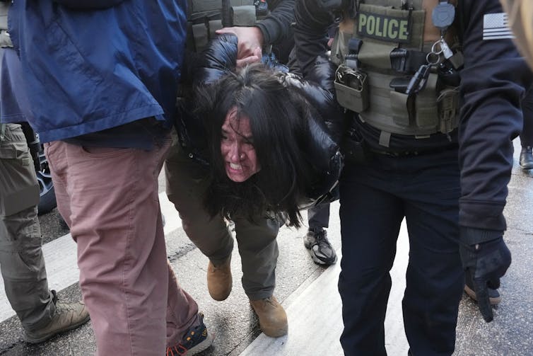 A woman is detained by federal agents.